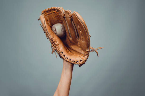 istock Baseball leather glove with white ball on hand on dark gray background. 1391626144