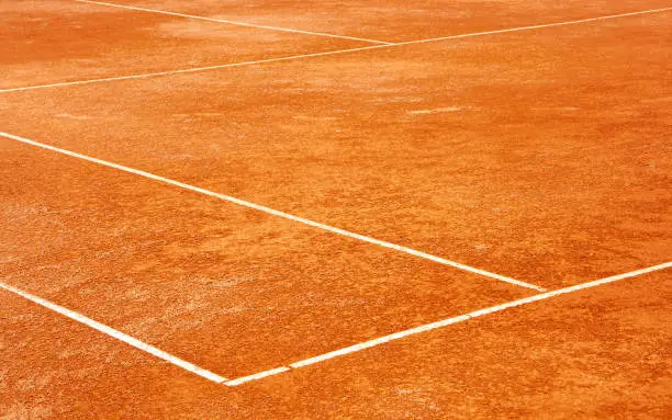 Clay tennis court. Surface outside back and side lines. Diagonal View.