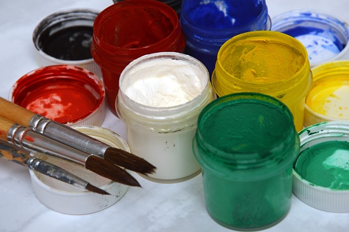 multicolor jars with colored paint and artistic brushes