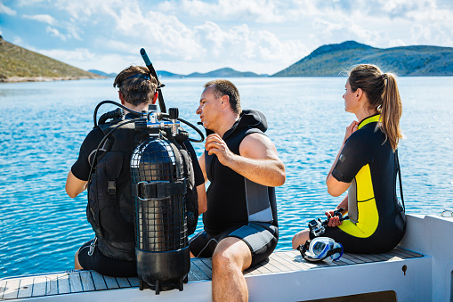 divers in black scuba diving suits with oxygen bottles sink under the sea, Scuba dive training in the sea with a instructor teaching students
