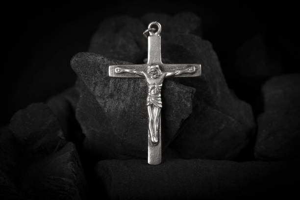 istock Silver crucifix necklace cross on pieces of coal. 1391637260
