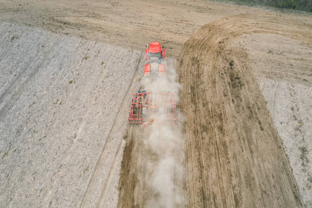 Red tractor plowing farm field aerial view looking down from above through clouds. Cultivation machine equipment working ploughing countryside arable soil driven by farmer spring planting tractor rojo arando la vista aérea del campo de la granja mirando hacia abajo desde arriba a través de las nubes. equipo de máquina de cultivo fotográfico con drones que trabaja arando suelo cultivable en el campo impulsado por la siembra de primavera