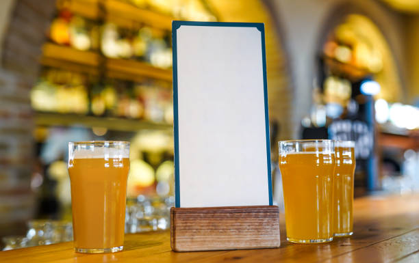 Glass of beer in a bar on a wooden table. Mock up Menu frame on Table stock photo