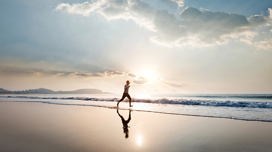 Man jogging on the beach at sunset.