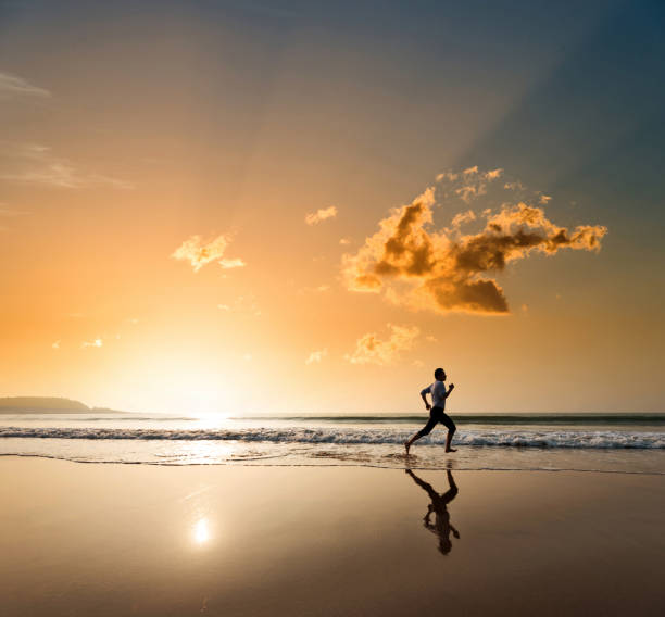 istock Man jogging on the beach at sunset 1391640779