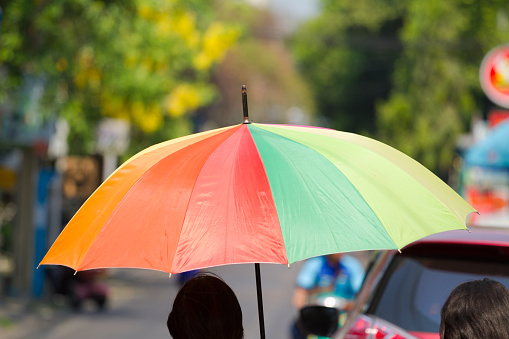 Thai woman with rainbow colored umbrella as sun protection
