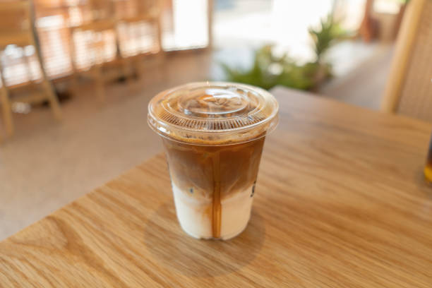 istock cold brewed iced latte coffee, showing separate in a layer the bottom as milk top by coffee shot in a plastic glass on wooden table in restaurant and cafe 1391641517