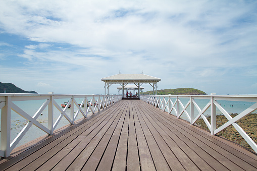 View along historical wooden pier at coast of Koh Sichang. Pier is near public park at Phra Chudahut Ratchathan Palace and Koh Sichang anchorage. In background are thai people and visitors of island