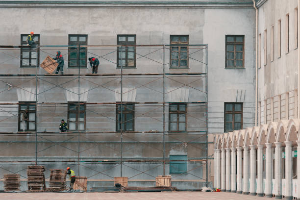 arbeiter reparieren ein altes historisches haus. bauherren auf gerüsten am gebäude. - restoring house scaffolding history stock-fotos und bilder