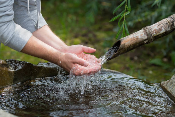 istock Mountain spring. A man washes his hands in a bowl with fresh, natural, cold drinking water. Ecology of the planet. Close-up. Japanese style. 1391646367