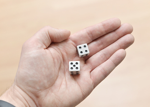 Closeup of generic white dice in a man's hand.