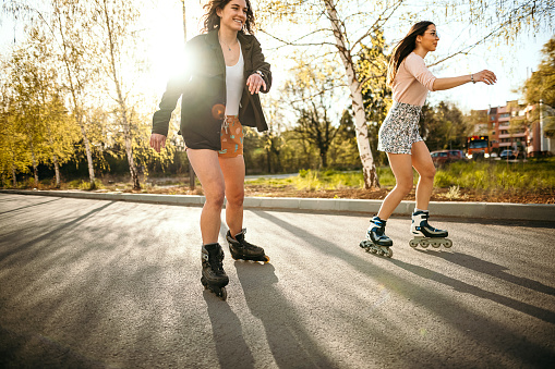 Two girls driving inline skates on the road on a sunny day
