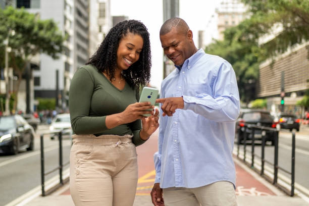 istock Man and woman using smart phone in the city. 1391651683