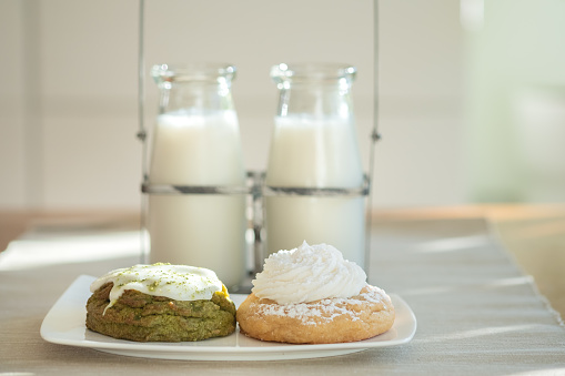 Vegan cookies made with natural ingredients:  matcha and lemon meringue, served with bottled almond milk.  Vancouver, British Columbia, Canada.