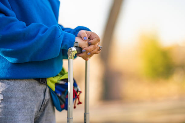 Blind mature adult man is walking with his white cane next to a blue metal wall in the city
