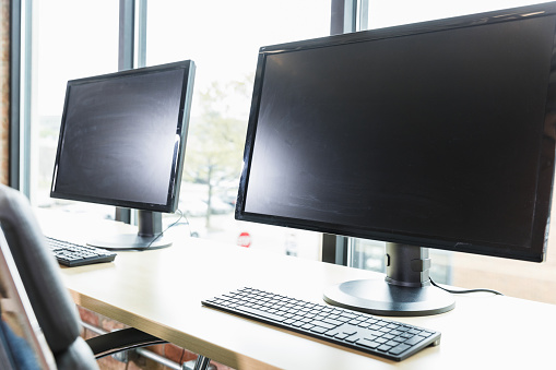 In the co-working space, two workstations with desktop PCs face the view through the floor to ceiling windows.