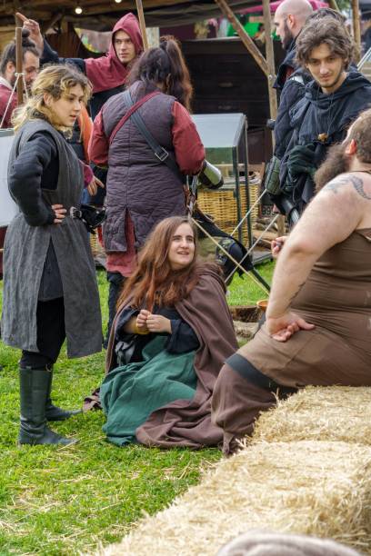 mulher sentada e vários homens durante uma recriação dos tempos medievais em um festival popular. - medieval market - fotografias e filmes do acervo