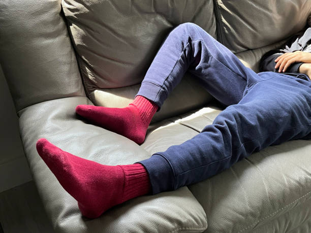 Detail of man laying down on a sofa wearing red socks