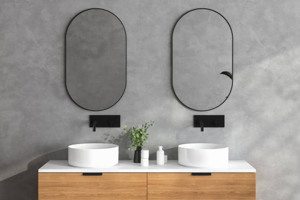 Close up of double sink with oval mirrors standing in on concrete wall , stock photo
