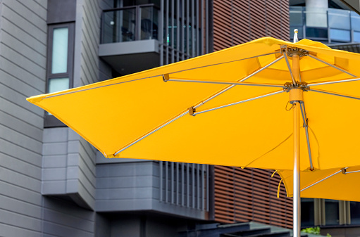 Yellow sunshade in city, background with copy space, full frame horizontal composition