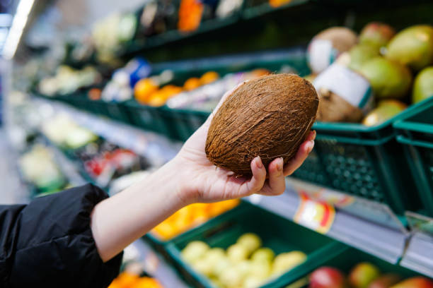 スーパーで熟したココナッツを選ぶ女性客。クローズアップ。 - farmers market ストックフォトと画像