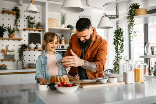 istock Father and daughter decorating cake in kitchen 1391679613