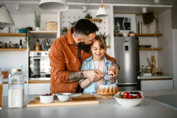 Little girl making and decorating cake with her father
