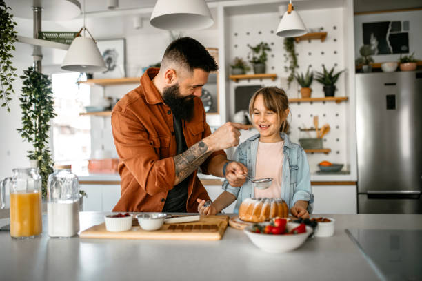 istock Father and daughter decorating cake in kitchen 1391679638