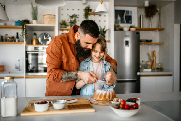 istock Father and daughter decorating cake in kitchen 1391679726