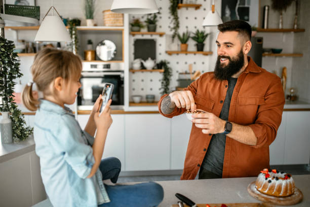 istock Daughter filming her father with smart phone while he is making a cake 1391679750