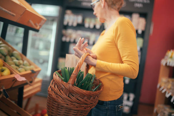 Female customer buying fresh organic vegetables in health food shop. stock photo