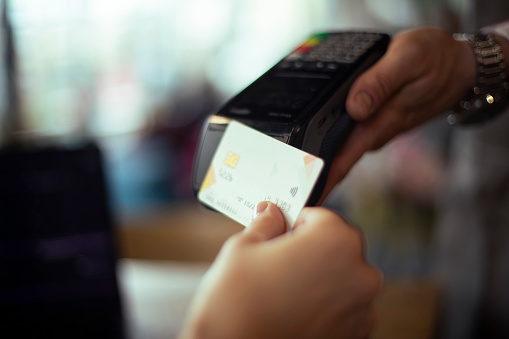 Close-up of a digital payment being made with a credit card and reader machine in a coffee shop.