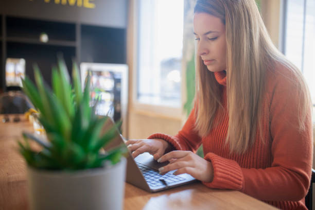 istock A focused woman dressed in a casual wardrobe writes a business email while sitting at a table. 1391685547
