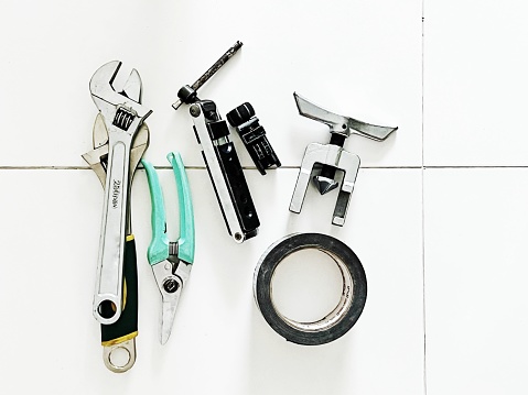 Overhead view of tools - Adjustable spanned, snip, masking tape, cutter tools flat lay on ceramic tile