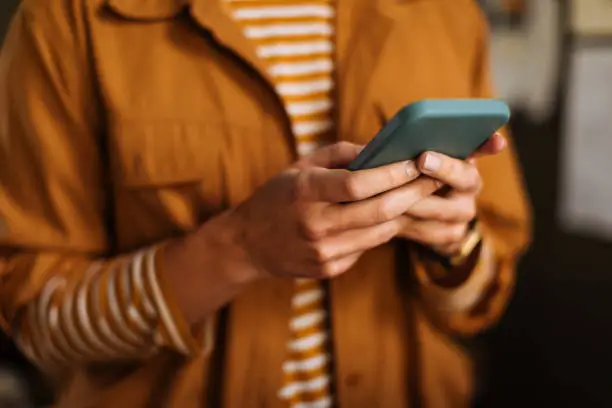 Shot of an unrecognizable woman using a mobile phone indoors