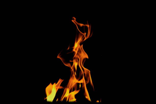 Close up burning flames on black background for graphic design or wallpaper. Red and yellow, heat energy igniting fuel during night. Abstract shaped fire used for cooking.