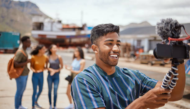 Shot of a young man using a digital camera on a tripod while hanging out with his friends outdoors