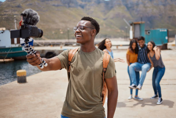 istock Shot of a young man using a digital camera on a tripod while hanging out with his friends outdoors 1391706486