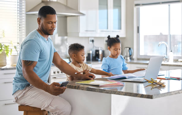 istock Shot of a young father using a phone while helping his children with homework at home 1391707324