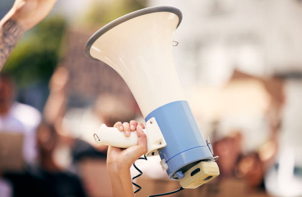 shot of a protester holding a megaphone during a rally - protest imagens e fotografias de stock