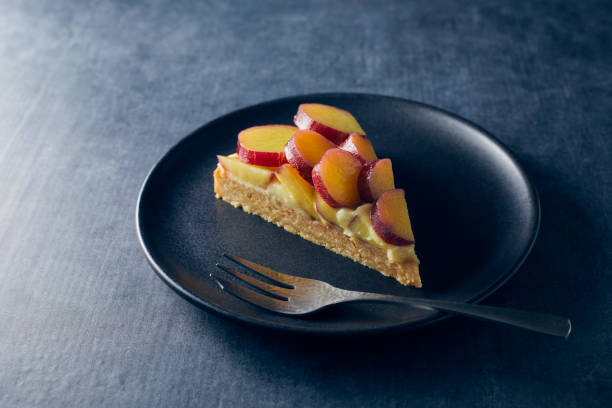 Carved sweet potato tart on a black plate with a fork.