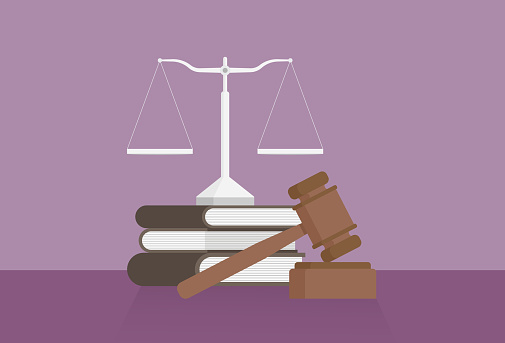 Equal-arm balance, a book, and a gavel on a table