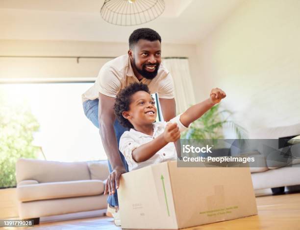Shot Of A Father Pushing His Son In A Box While Playing Together At Home Stock Photo - Download Image Now