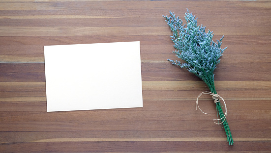 Flower bouquet and blank note paper on wood background, banner with copy space, top view, flat lay