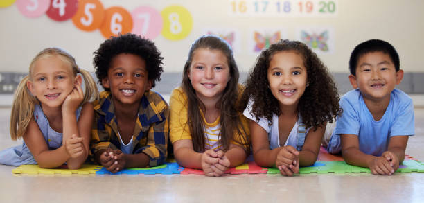 Shot of a group of kids laying on the floor in class Everyone loves story time elementary student stock pictures, royalty-free photos & images