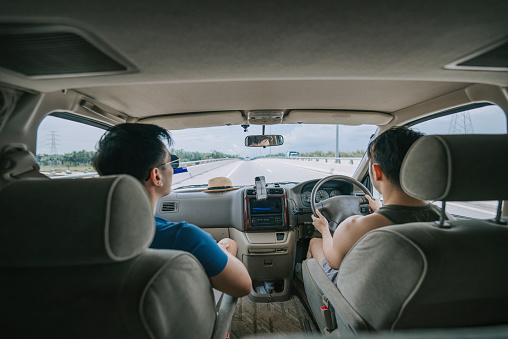 Asian Chinese Gay couple travelling using mobile app road map with campervan for vacation road trip during weekend