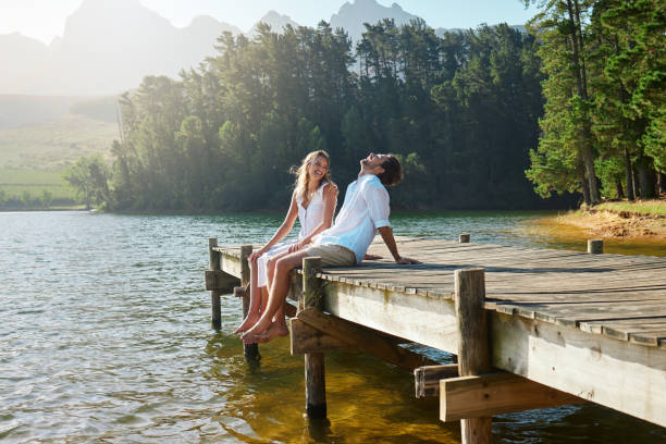 Shot of a young couple spending time together at a lake He's so funny jetty stock pictures, royalty-free photos & images
