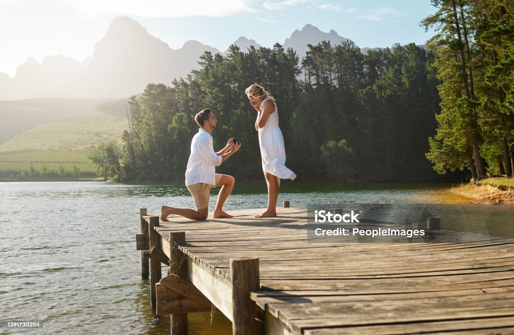 Shot of a young man proposing to his girlfriend in nature Forever with you sounds great Engagement Stock Photo