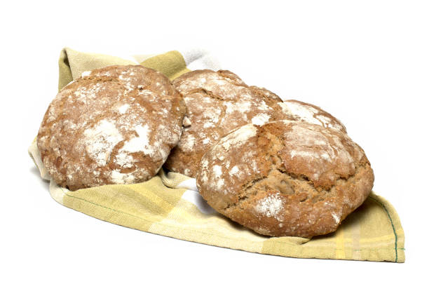 Close up of three freshly baked traditional Tyrolean South Tyrolean round loaves of bread called Vinschgerle on a kitchen towel and white background