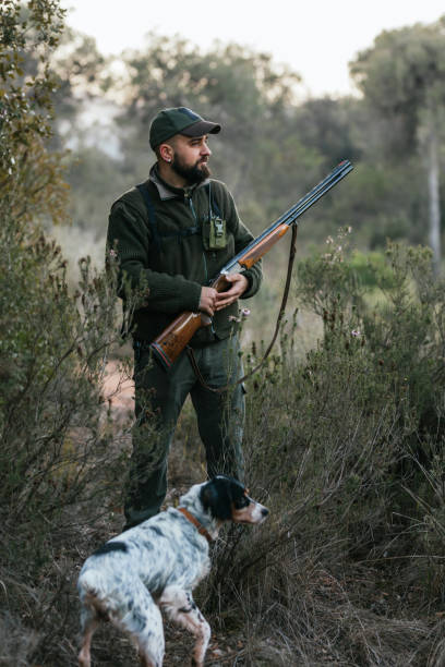 istock Hunter man with a gun standing outdoors with his dog while searching for a prey. 1391738941